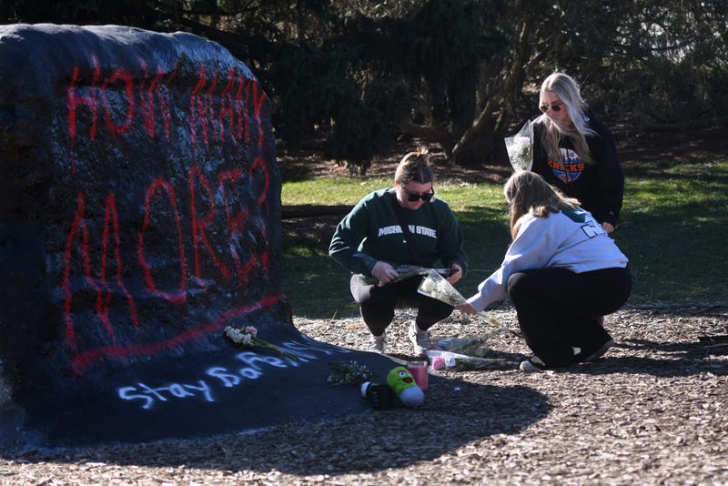 Students leave flowers at The Rock on MSU's campus following mass shooting