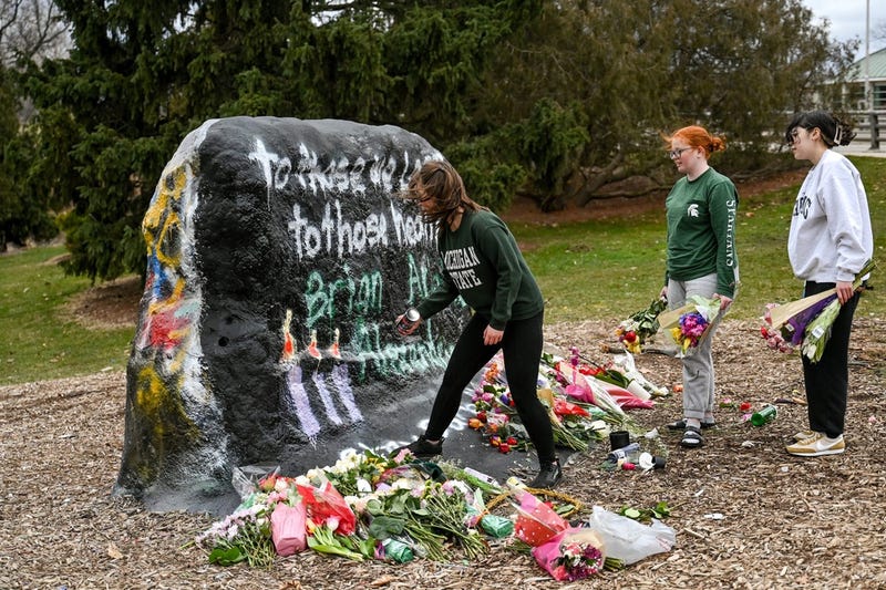Three Michigan State student who wished to only speak to university media paints The Rock at MSU with the message, \"To those we lost, to those healing, Brian, Arielle, Alexandria,\" on Wednesday, Feb. 15, 2023, on campus in East Lansing. The student and two others covered up the rock that was painted last night with the message, \"Allow us to defend ourselves, carry on campus.\"