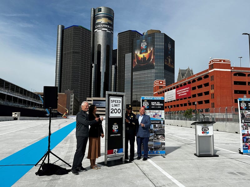 Officials pose next to 200 MPH speed limit sign on Detroit Grand Prix track near the Renaissance Center