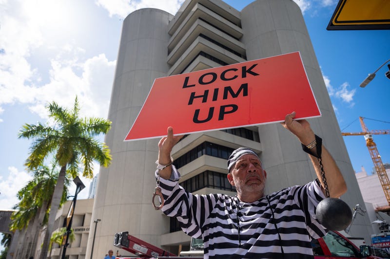 Dominic Santana, Miami, holds a sign reading "Lock him up" while wearing a striped prisoner's outfit outside the Wilkie D. Ferguson Jr. Courthouse on Tuesday, June 13, 2023, in Miami, Fla.