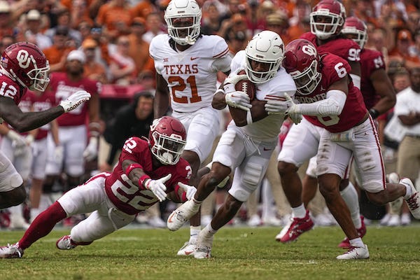 Texas running back Keilan Robinson (7) tries to avoid being tackled by two Oklahoma defenders during their game in 2022 at the Cotton Bowl
