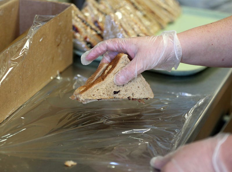 A cafeteria worker wraps peanut butter and jelly sandwiches