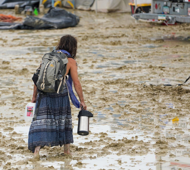 A Burning Man attendee makes their way through the mud