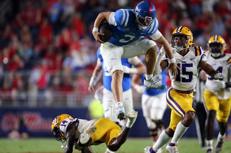 Mississippi Rebels quaterback Jaxson Dart leaps over LSU Tigers defensive back Andre' Sam