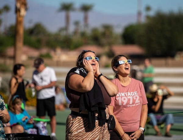 Women wearing eclipse glasses staring at solar eclipse