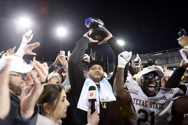 Texas State Bobcats head coach GJ Kinne holds up the trophy after his team defeated the Rice Owls at Gerald J Ford Stadium