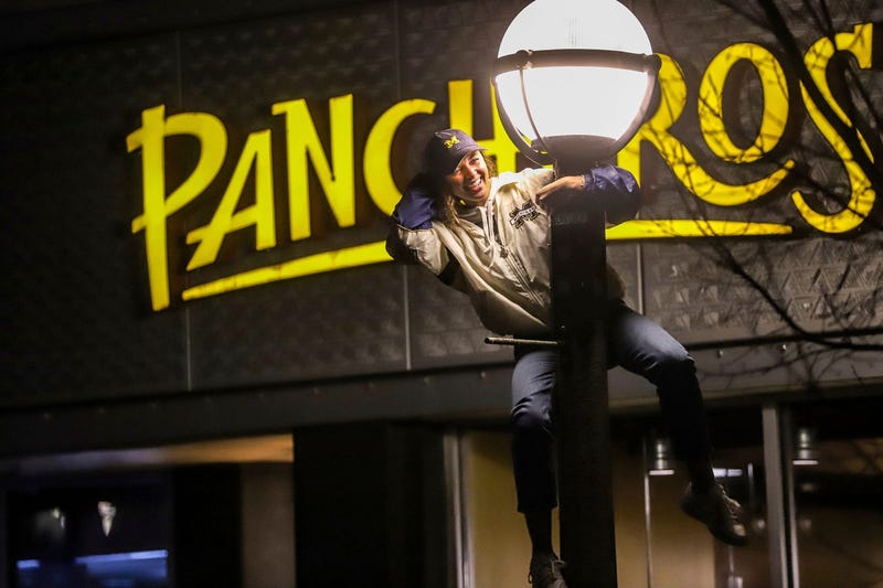 A Michigan Wolverine fan climbs a light pole to celebrate their win in the College Football National Championship against Washington in Ann Arbor, Mich. on Monday, Jan. 8, 2024.
