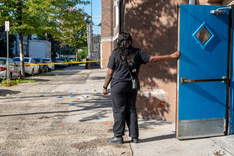 A person steps outside of the school to take a look at the remains of medical supplies after a stolen car chase ended in a police-involved shooting outside of Hawthorne Avenue Elementary School in Newark on Tuesday, August 13, 2024