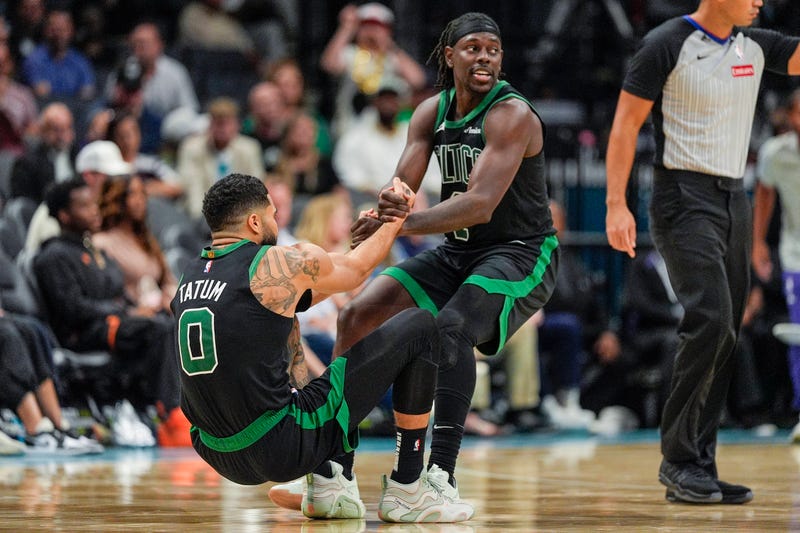Boston Celtics guard Jrue Holiday (4) helps forward Jayson Tatum (0) onto his feet after a foul late during the second half against the Charlotte Hornets at the Spectrum Center.