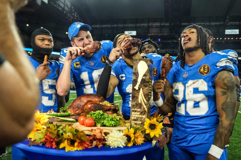 Lions quarterback Jared Goff (16), defensive tackle DJ Reader (98), wide receiver Amon-Ra St. Brown (14), running back Jahmyr Gibbs (26) and linebacker Al-Quadin Muhammad (69) celebrate their win against the Bears with a turkey drumstick Thanksgiving Day in Detroit.