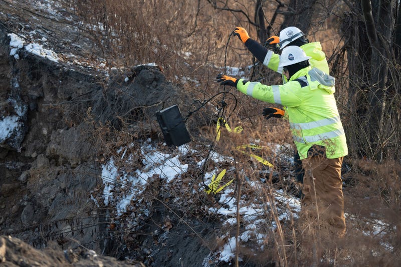 Construction worker toss a piece of equipment in the sinkhole on I-80 East in Wharton on Friday, Dec. 27, 2024