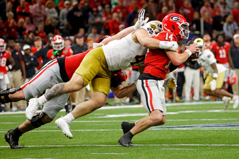 Jan 2, 2025; New Orleans, LA, USA; Georgia Bulldogs quarterback Gunner Stockton (14) runs with the ball during the second half as Notre Dame Fighting Irish defensive lineman Donovan Hinish (41) goes for a tackle at Caesars Superdome. Mandatory Credit: Amber Searls-Imagn Images