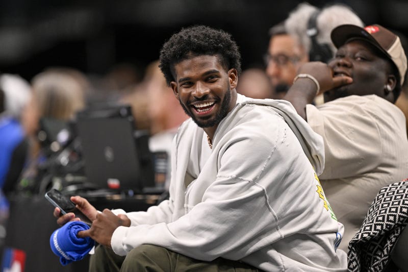 Jan 14, 2025; Dallas, Texas, USA; Colorado Buffaloes quarterback Shedeur Sanders laughs as he watches the game between the Dallas Mavericks and the Denver Nuggets during the second half at the American Airlines Center.