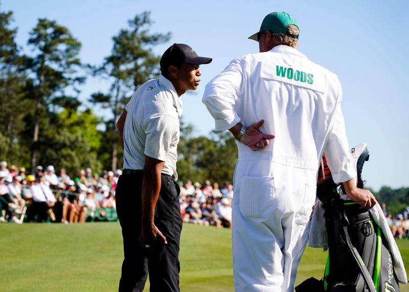 Apr 13, 2024; Augusta, Georgia, USA; Tiger Woods talks with his caddie Lance Bennett while holding the back of his leg on the No. 18 green during the third round of the Masters Tournament. Mandatory Credit: Katie Goodale-USA TODAY Network