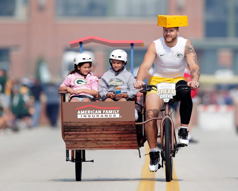 Green Bay Packers tight end Tucker Kraft (85) wears a cheesehead while participating in the Dream Drive bicycle ride before the start of practice on July 31, 2025, in Ashwaubenon, Wis.