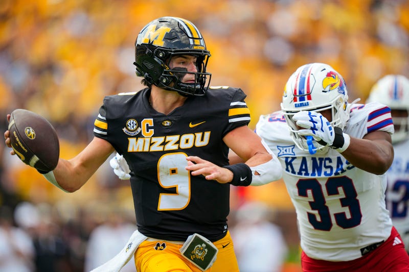Missouri Tigers quarterback Beau Pribula (9) rolls out to pass against Kansas Jayhawks defensive end Leroy Harris III (33) during the first half at Faurot Field at Memorial Stadium.