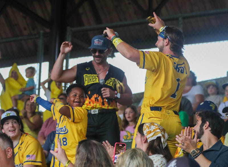 Savannah Bananas catcher Bill LeRoy and Firefighters pitcher Marshall Shill celebrate with a young fan during the first game of the Banana Ball Championship series on Thursday, October 2, 2025 at Historic Grayson Stadium.