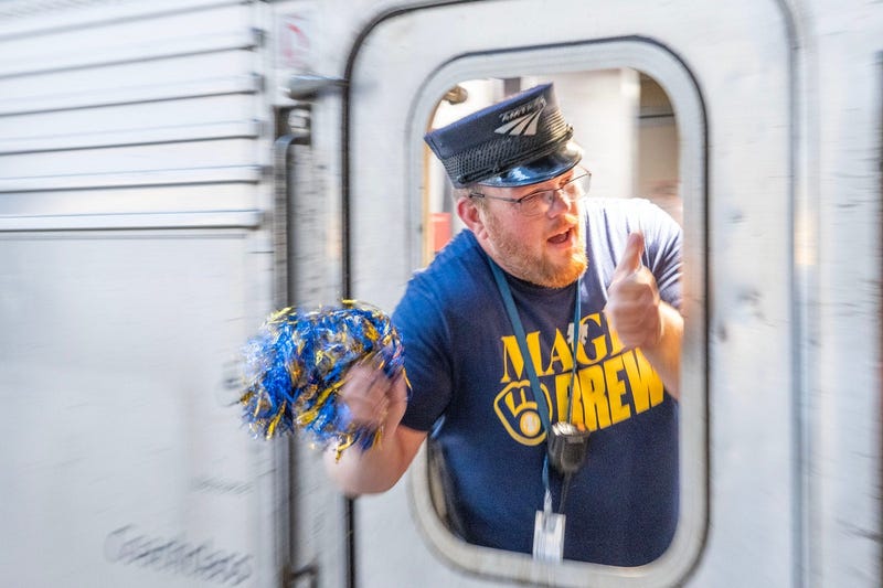 Amtrak train conductor, Ben Miller waves a Brewers colored pompom as the Amtrak Hiawatha train leaves the Milwaukee Intermodal Station in Milwaukee, Wisconsin on Oct. 8, 2025, headed for Chicago to watch the Milwaukee Brewers take on the Chicago Cubs in Game 3 of National League Division Series playoff baseball game.