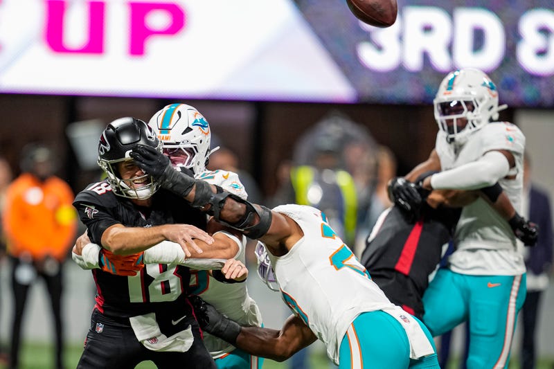 Atlanta Falcons quarterback Kirk Cousins (18) is hit by Miami Dolphins linebacker Jaelan Phillips (15) and linebacker Jordyn Brooks (20) as he releases the ball during the first quarter at Mercedes-Benz Stadium.