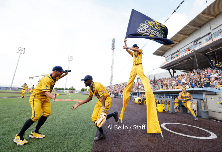 Two Savanah Banana players slap hands while another stands on stilts