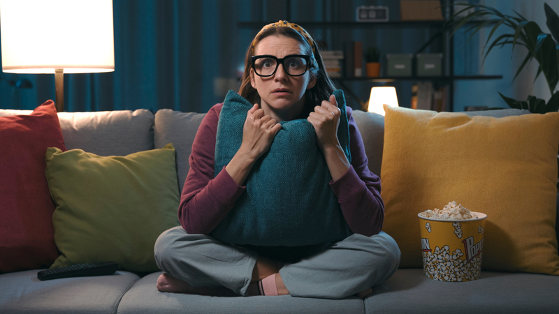 scared woman watching movie on couch