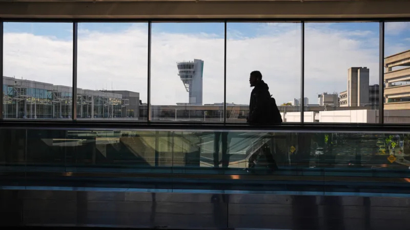 A traveler moves in view of a control tower at Philadelphia International Airport on Nov. 5, 2025.