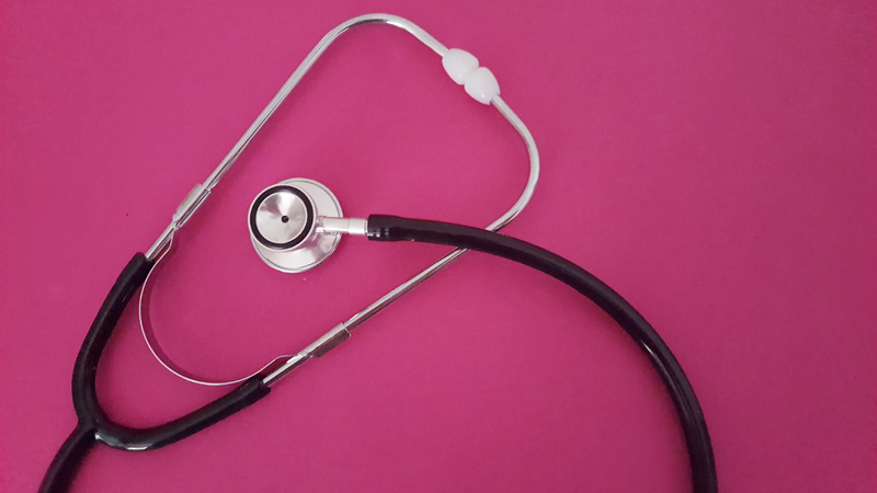 Stethoscope on pink background with space for text , top view