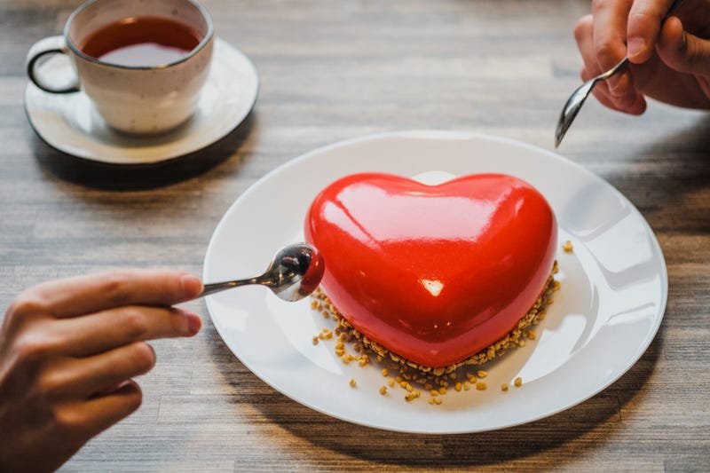 A couple share a large heart-shaped dessert over coffee