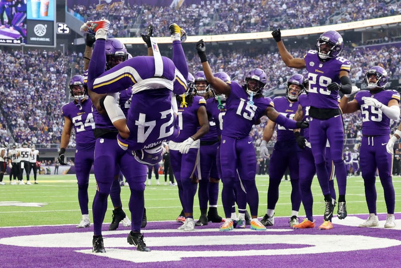 Josh Metellus #44 of the Minnesota Vikings flips teammate Camryn Bynum #24 after intercepting a pass against the Atlanta Falcons during the second quarter at U.S. Bank Stadium on December 08, 2024 in Minneapolis, Minnesota.