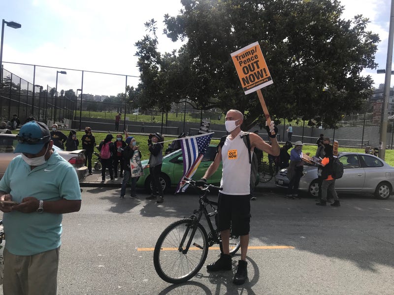 A man holds a sign reading "Trump/Pence Out Now" at a rally in San Francisco.