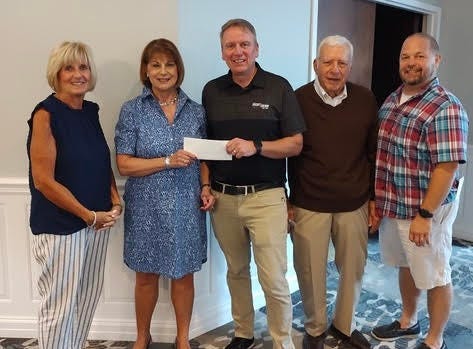 Warm the Children Volunteer Coordinator Liz Angelbeck receives a check from West Herr Auto Group to purchase new winter clothing for children in need