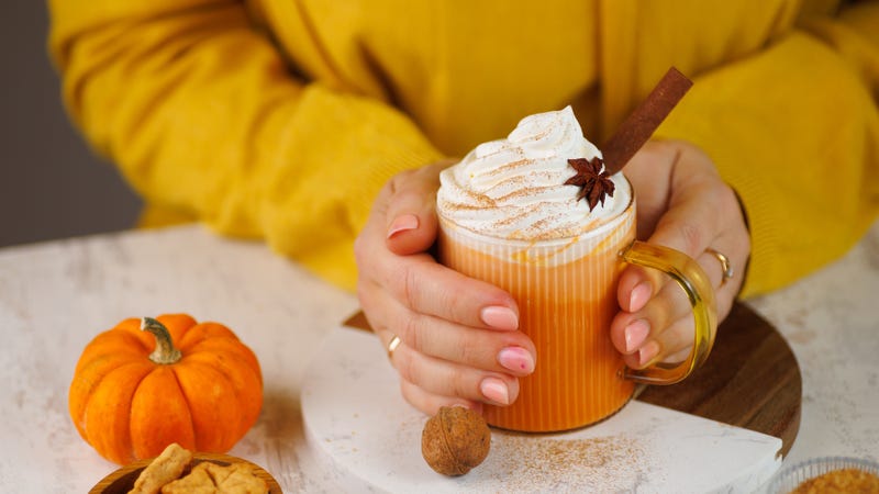 Woman holding cup of pumpkin spice latte with whipped cream