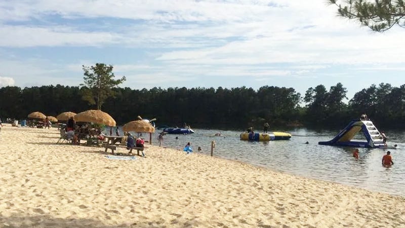 lake with inflatables on water and shade umbrellas on sand