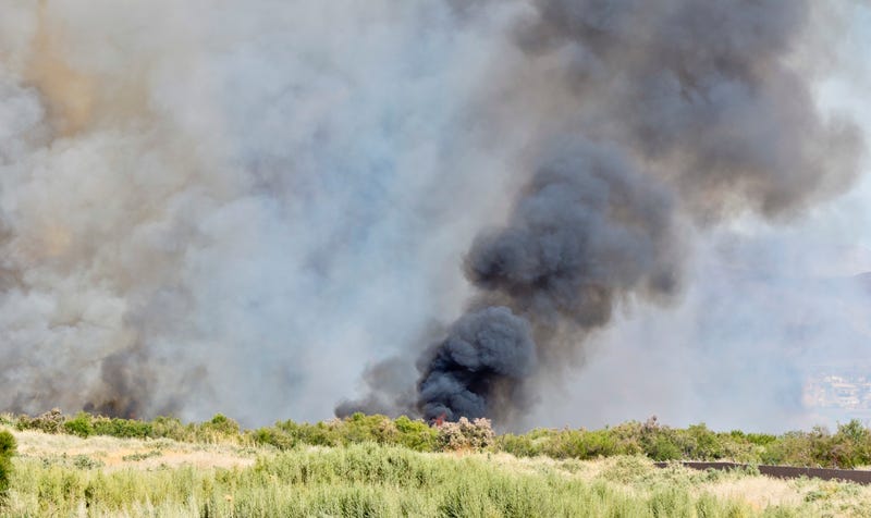 A brush fire burns a grassy field in Las Vegas creating dark smoke.