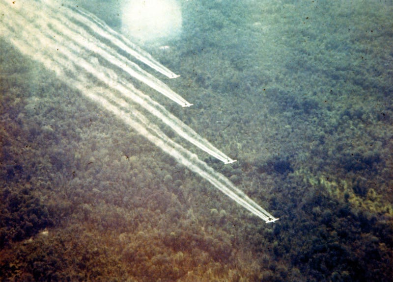 Aircraft spray Agent Orange over forested areas.