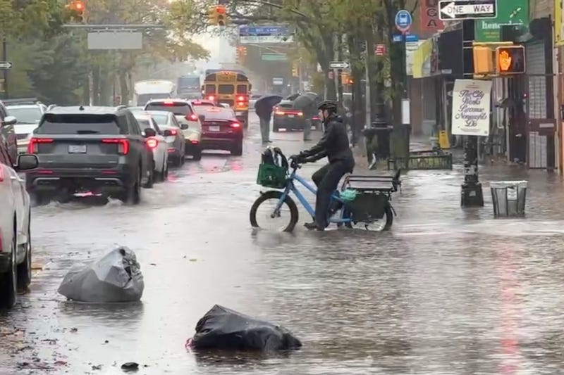 A cyclist rides through floodwaters during a rainstorm in New York, Thursday, Oct. 30, 2025