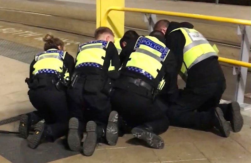 Police restrain a man after he stabbed three people at Victoria Station in Manchester, England, late Monday Dec. 31, 2018