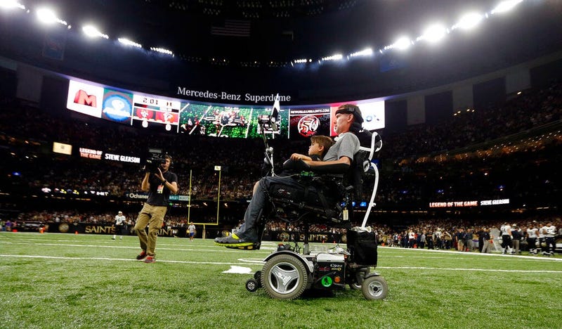 former New Orleans Saints player Steve Gleason rides onto the field with with his son Rivers before an NFL football game against the Atlanta Falcons in New Orleans