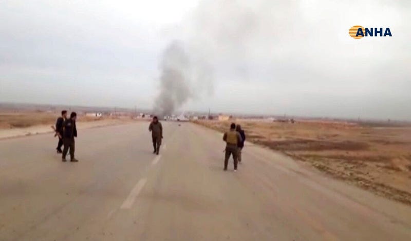 This frame grab from video provided by Hawar News, ANHA, the news agency for the semi-autonomous Kurdish areas in Syria, shows Kurdish fighters standing guard at the site of a suicide attack near the town of Shaddadeh, in Syria's northeastern province of 