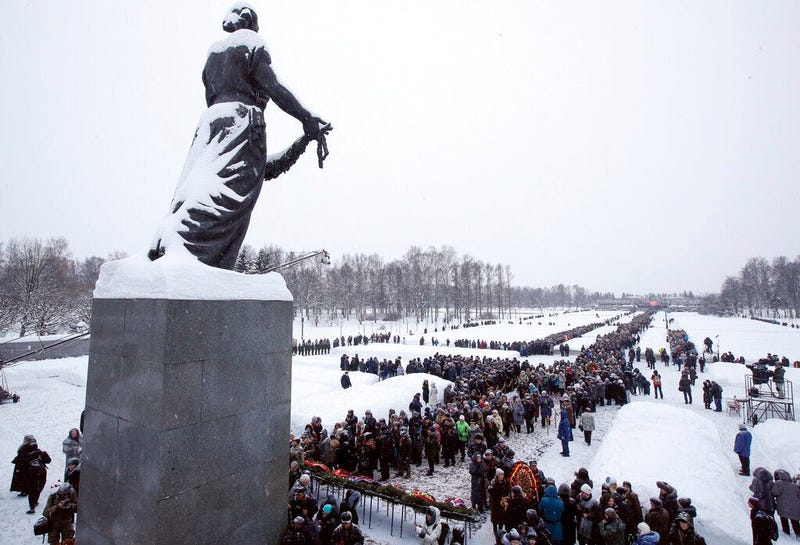People walk in snowfall to the Motherland monument to put flowers at the Piskaryovskoye Cemetery where most of the Leningrad Siege victims were buried during World War II