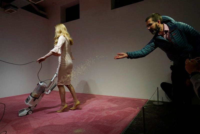 A spectator tosses crumbs for an Ivanka Trump lookalike to vacuum at Jennifer Rubell's art exhibit "Ivanka Vacuuming 2019" on Tuesday, Feb. 5, 2019