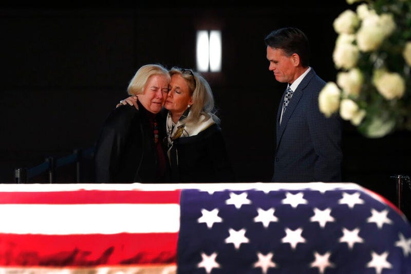 Rep. Debbie Dingell, D-Mich., center, consoles former Rep. Candice Miller, R-Mich., as Macomb County executive Mark Hackel, right, looks on at the casket of her husband and former Rep. John Dingell, lying in repose in Dearborn, Mich., Monday, Feb. 11, 201