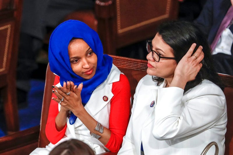 Rep. Ilhan Omar, D-Minn., left, joined at right by Rep. Rashida Tlaib, D-Mich., listens to President Donald Trump's State of the Union speech