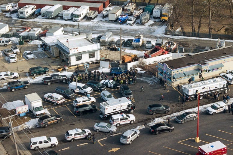 Law enforcement personnel gather near the scene of a shooting at an industrial park in Aurora