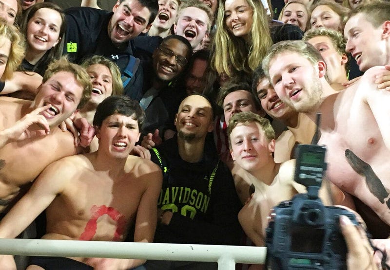 Golden State Warriors' Stephen Curry, center, poses with the Davidson College swim team as he takes in an NCAA college basketball game at his alma mater Friday, Feb. 15, 2019, while back in his hometown of Charlotte, N.C., for the NBA basketball All-Star 
