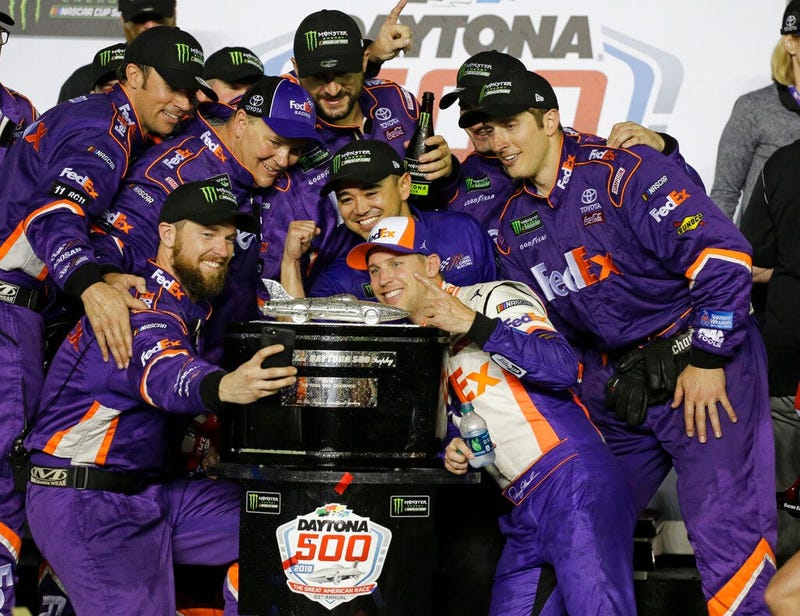 Denny Hamlin, center front, poses for a photo with his crew members after winning the NASCAR Daytona 500 auto race at Daytona International Speedway, Sunday, Feb. 17, 2019, in Daytona Beach, Fla