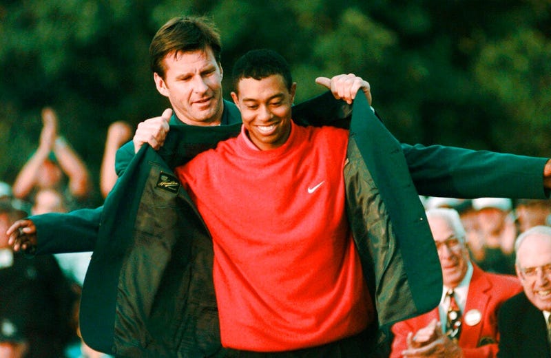 April 13, 1997, file photo, Masters champion Tiger Woods receives his Green Jacket from last year's winner Nick Faldo, rear, at the Augusta National Golf Club in Augusta, Ga. Woods completes an amazing journey by winning the 2019 Masters, overcoming 11 ye