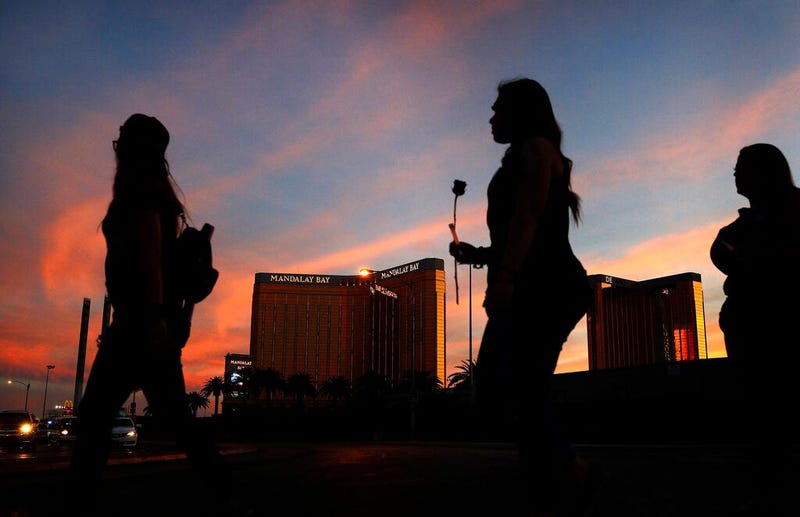  people carry flowers as they walk near the Mandalay Bay hotel and casino during a vigil for victims and survivors of a mass shooting in Las Vegas.