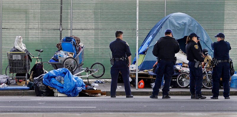, San Francisco police officers wait while homeless people collect their belongings in San Francisco