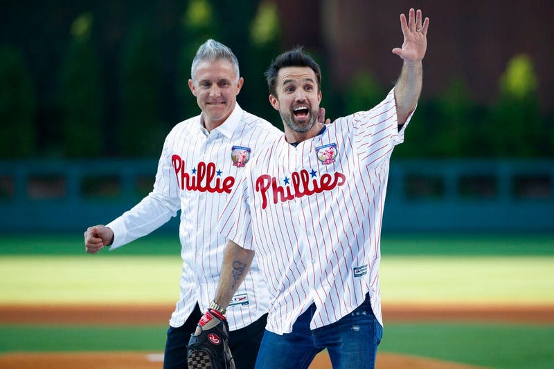 Actor Rob McElhenney, right, one of the creators of "It's Always Sunny in Philadelphia," reacts after catching a ceremonial first pitch from former Philadelphia Phillies player Chase Utley
